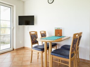 Cozy reading nook with a round table, cushioned chairs, and a flat-screen TV.
