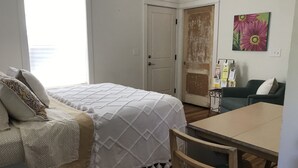 Une chambre à coucher avec un lit, une chaise, une table et une porte.