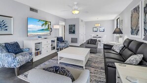 Un salon moderne doté d’un téléviseur à écran plat, d’un ventilateur de plafond et d’un coin repas.