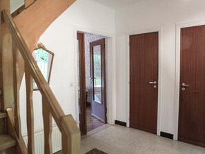 A hallway with a wooden staircase, a door with a window, and a door with a wooden frame. - Westmalle Forest Garden Home (Malle)