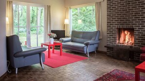 Un salon confortable avec une cheminée, un canapé, un fauteuil et un téléviseur.