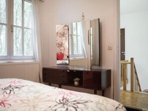 A bedroom with a bed, a dresser, a mirror, and a window with curtains. - Westmalle Forest Garden Home (Malle)