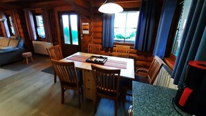 A cozy cabin interior with a dining table, chairs, a sofa, and a window with curtains. - Family Getaway in Dankerode (Harzgerode)