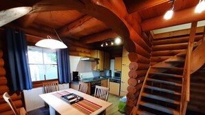 A log cabin interior with a dining area, kitchen, and a spiral staircase. - Family Getaway in Dankerode (Harzgerode)