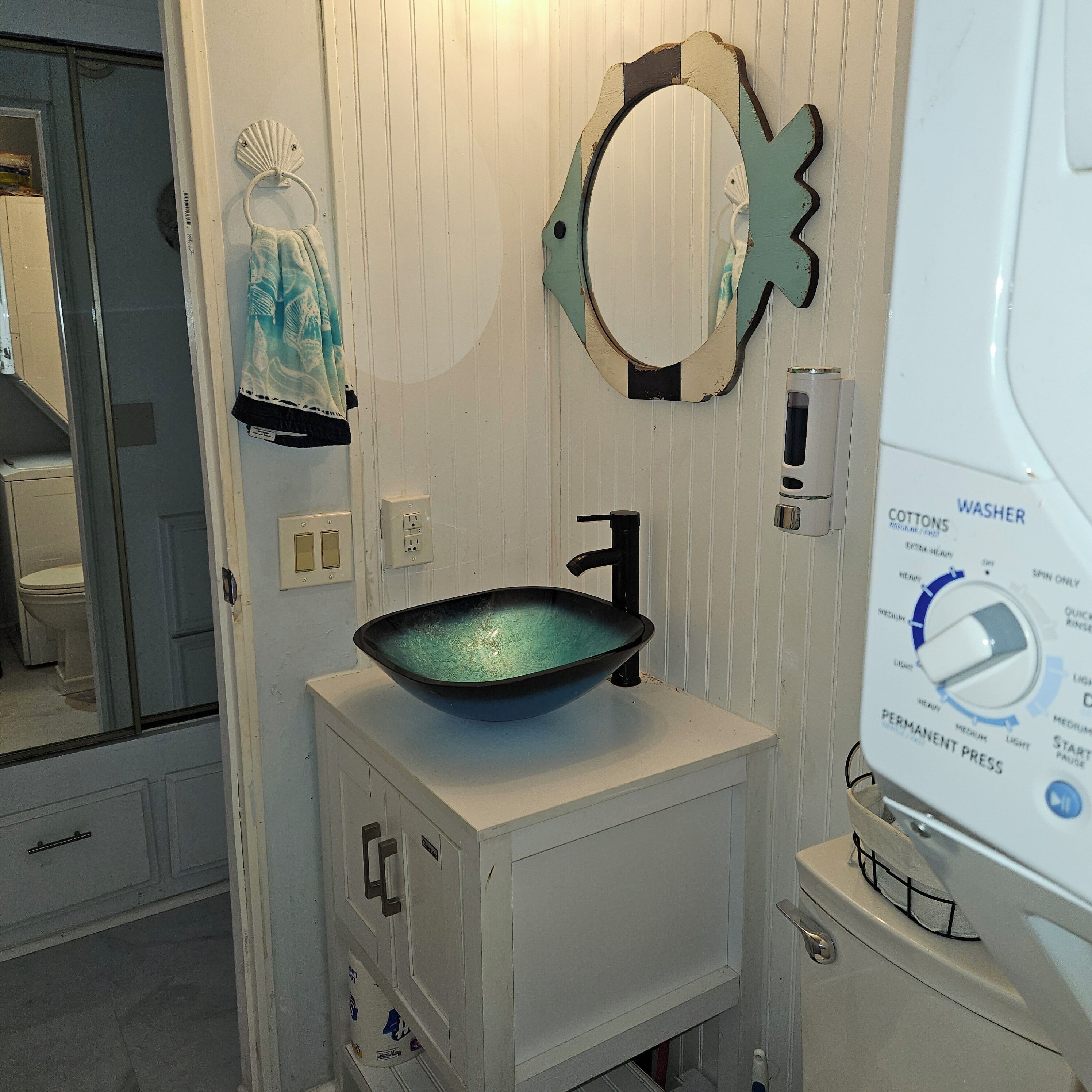 A bathroom with a white sink, a mirror, and a hand dryer.