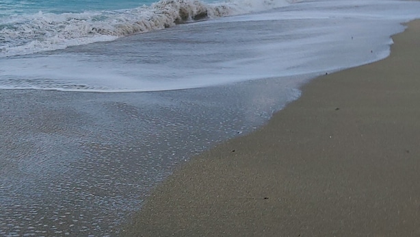 Een strand met een rotsachtige kustlijn en een heldere lucht.