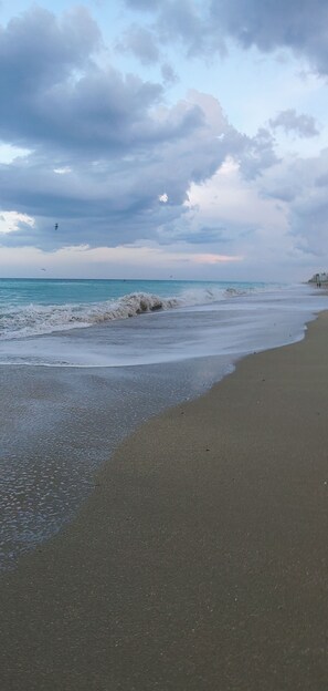 Une plage bordée d’une côte rocheuse, sous un ciel dégagé.