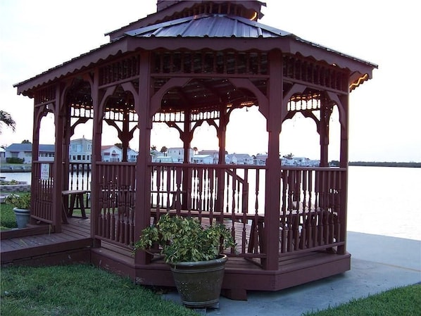 Un kiosque doté d’un toit en métal, de garde-corps en bois et d’un banc.