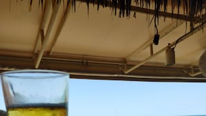 Een glas bier op een houten toog, met uitzicht op de oceaan.
