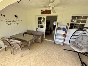 Une pièce comprenant une table à manger, un canapé, des chaises, un ventilateur de plafond et un fauteuil suspendu.