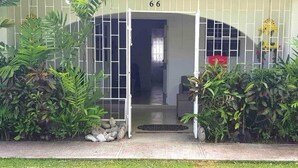 A building with a gated entrance, number 66, and a small porch area with plants. - West Coast 1 Bedroom Apartment - Close to beach (66) (Holetown)