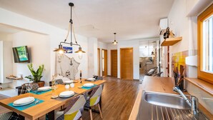 Eine moderne Küche mit Holzboden, einem Edelstahl-Spülbecken und einem Essbereich mit Holztisch und -stühlen.