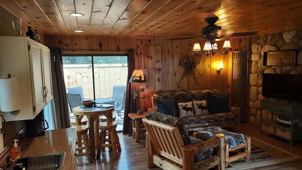 Een gezellig interieur van een blokhut met een houten eettafel, stoelen, een bank en een stenen open haard.