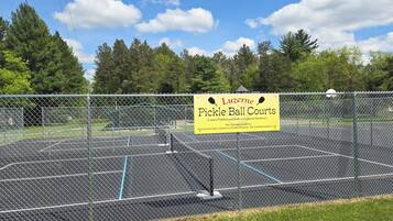 Una cancha de pádel vallada con un letrero que anuncia equipos Luzerne Hardware.