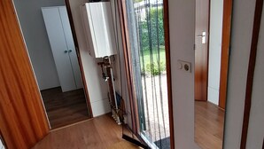 Un pasillo con suelo de madera, una puerta corrediza de vidrio que da a un balcón y un radiador blanco.