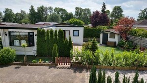 Una casa móvil con garaje, un pequeño jardín y entrada pavimentada.