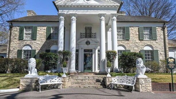 A large stone building with a central entrance flanked by columns, statues, and a green door. - Craftsman Guest Suite | Heart of Cooper-Young (Memphis)