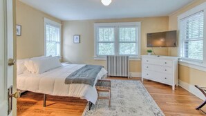 A bedroom with a bed, dresser, radiator, and a TV on the wall. - Craftsman Guest Suite | Heart of Cooper-Young (Memphis)