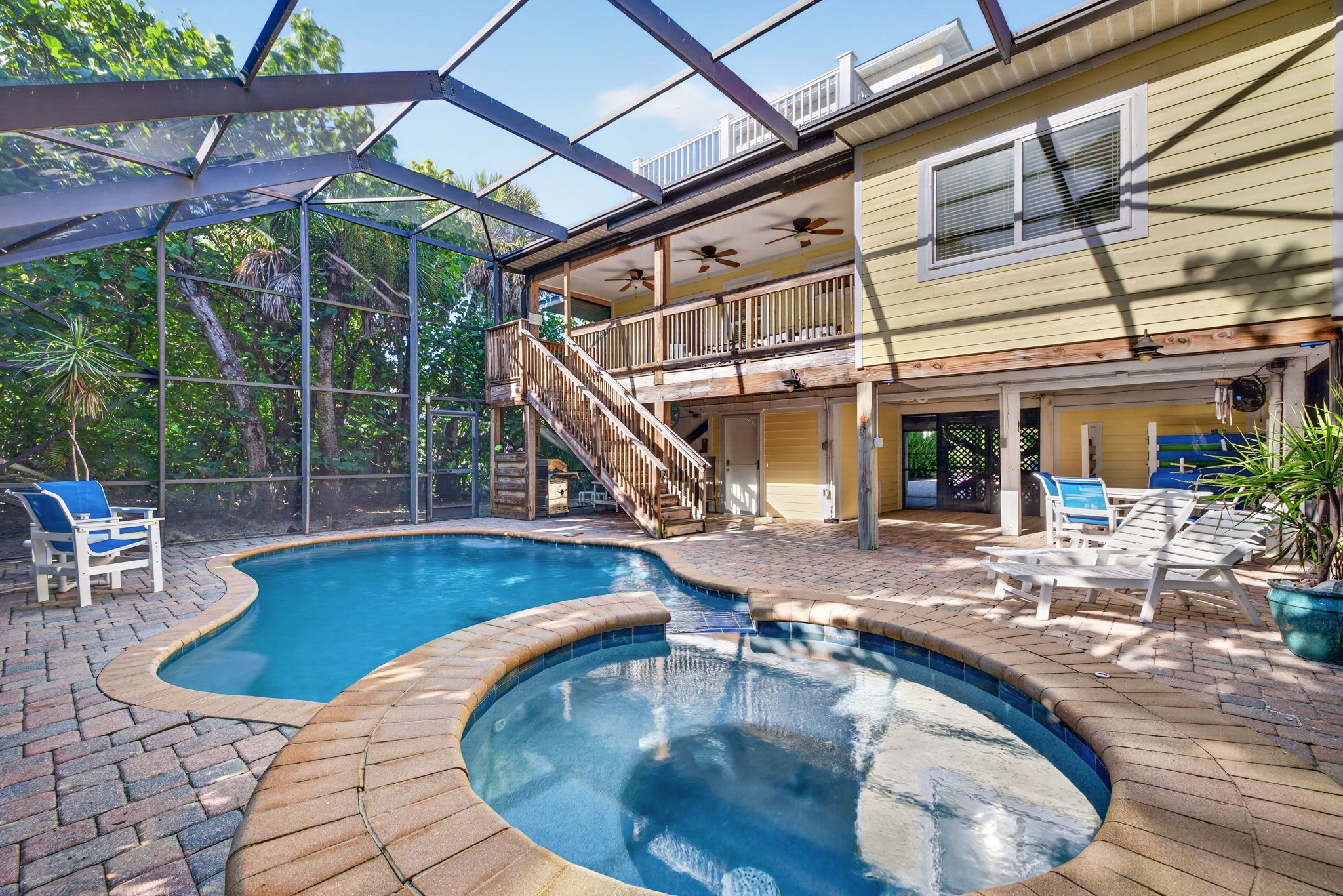 A swimming pool with a hot tub, surrounded by a covered patio area with outdoor furniture.