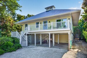 A two-story house with a covered porch, a staircase, and a gravel driveway.
