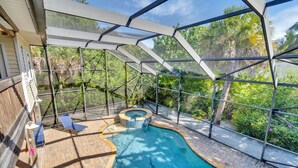 A covered outdoor swimming pool with a hot tub, lounge chairs, and a view of tropical foliage. - Dream home with incredible outdoor space. Walk to beach & restaurants! (Sanibel)