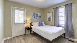 Un dormitorio con cama, mesita de noche, lámpara y obras de arte en las paredes.