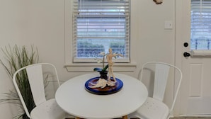 Una mesa de comedor blanca con dos sillas blancas, una planta pequeña en maceta y una estatua decorativa sobre la mesa.