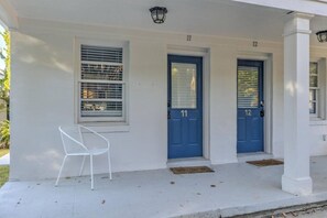 A white building with two blue doors labeled 11 and 12, a white chair, and a small porch area.