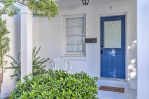 Un edificio blanco con una puerta azul, una ventana y un felpudo.