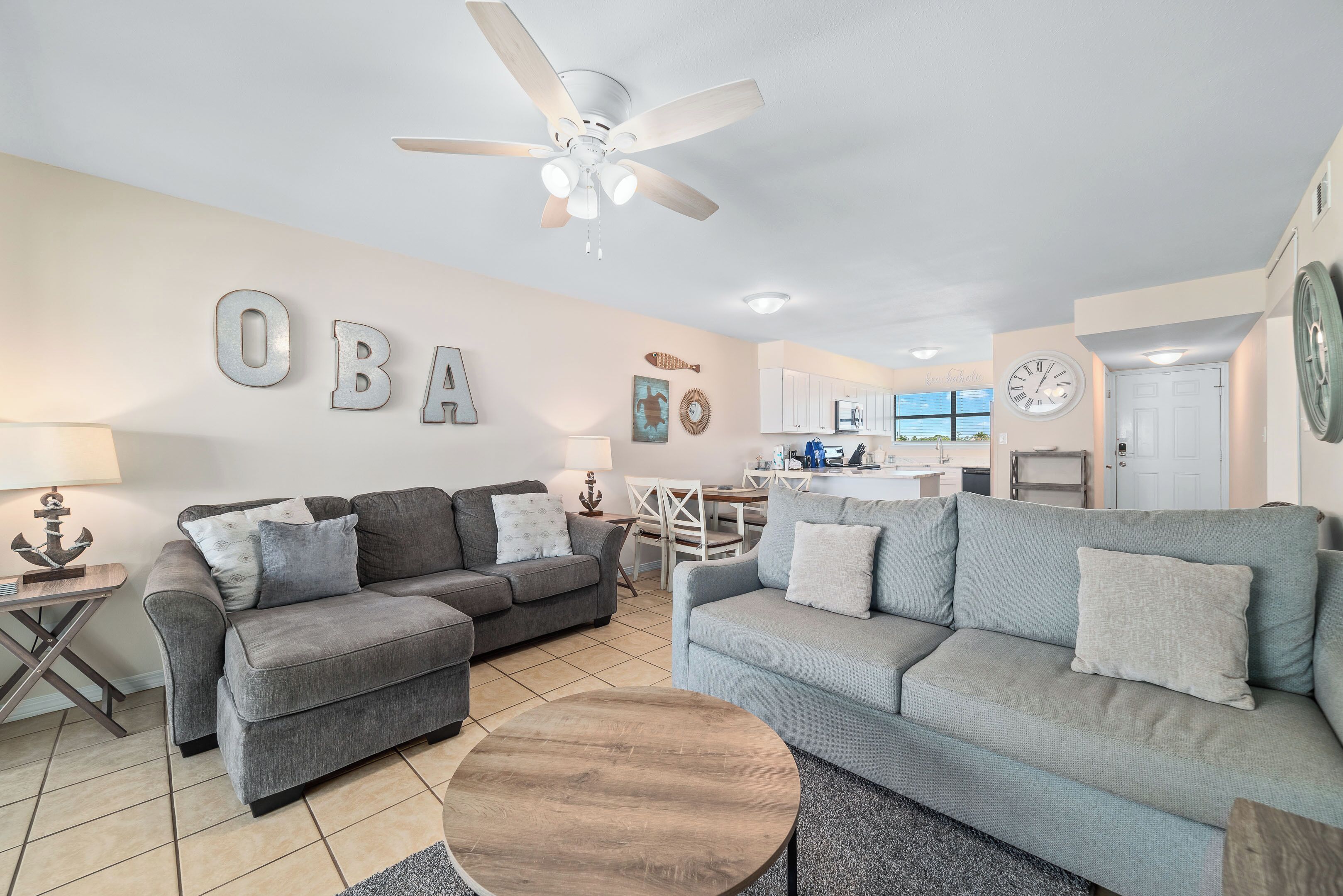 A living room with two grey sofas, a wooden coffee table, and a ceiling fan.