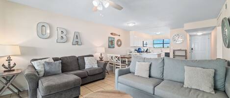 A living room with two grey sofas, a wooden coffee table, and a ceiling fan.