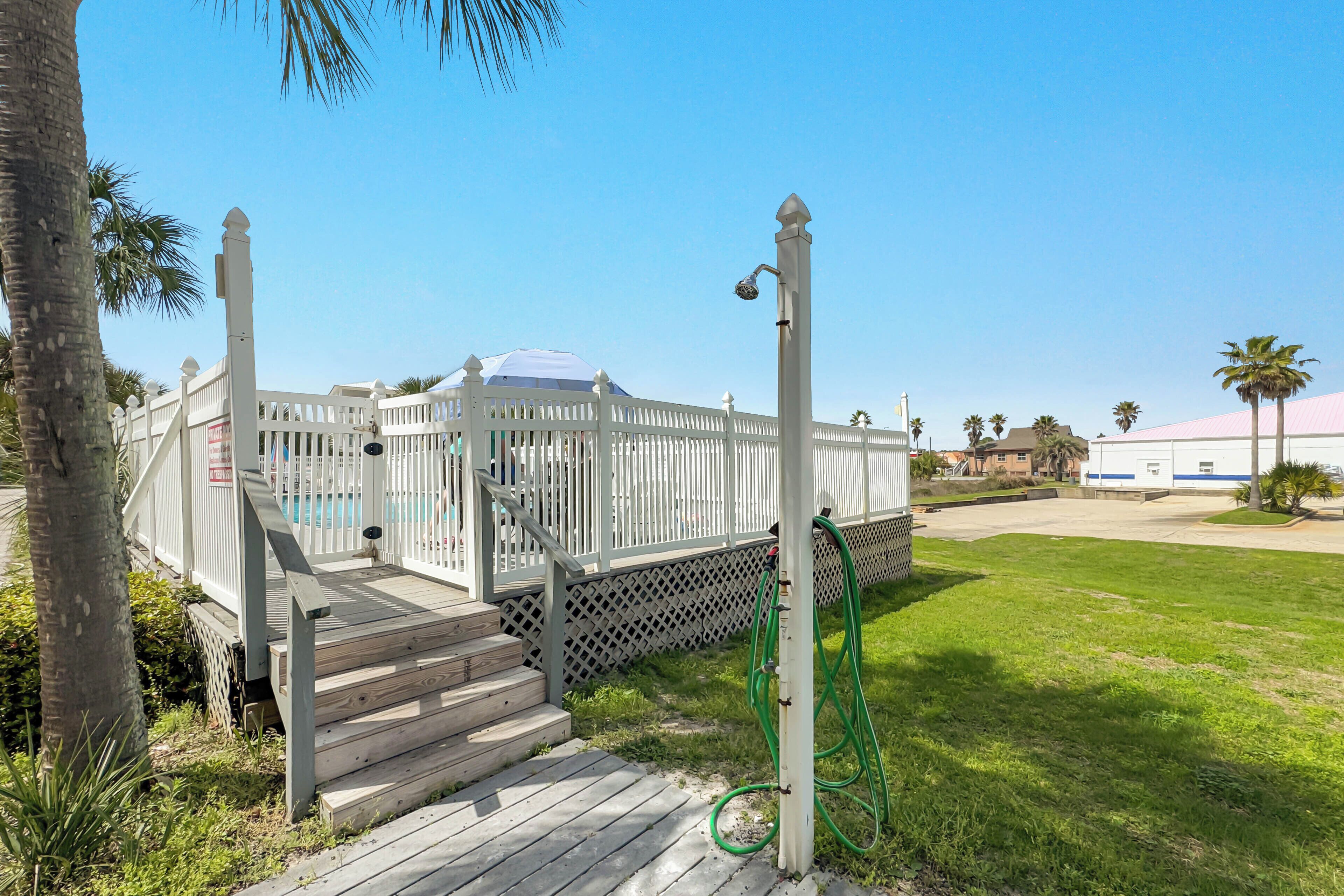 A white fence, a pool, and a grassy area.