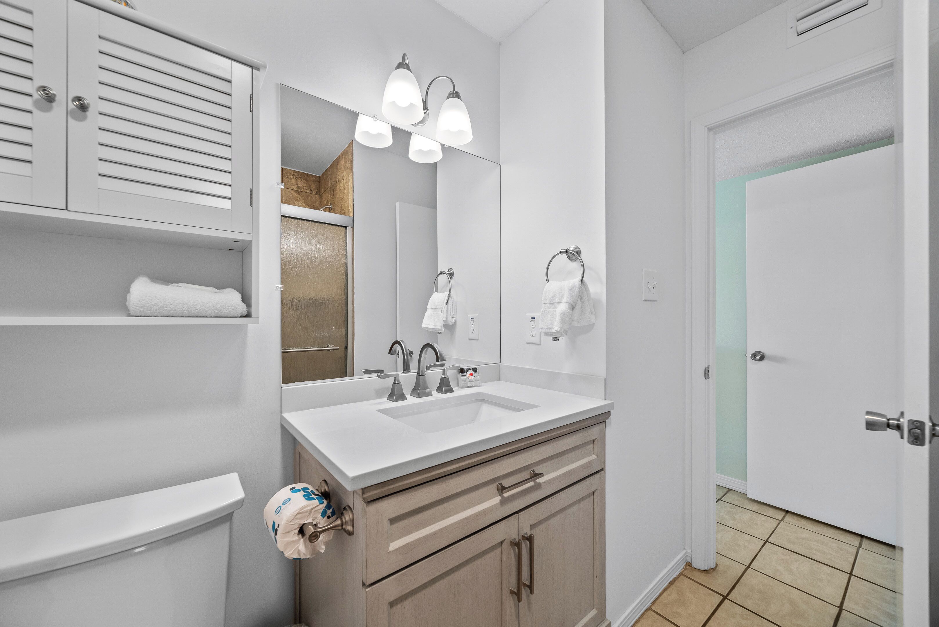 A bathroom with a white sink, a mirror, and a towel rack.