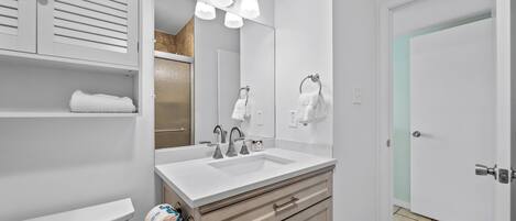 A bathroom with a white sink, a mirror, and a towel rack.