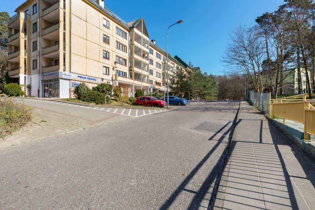 A multi-story hotel with a flat facade, a visible entrance, and a parking area with cars.