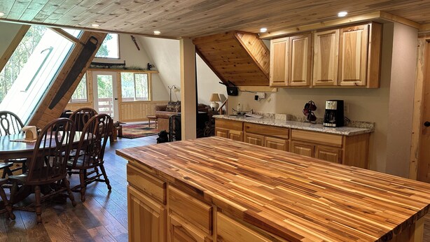 A spacious kitchen with wooden cabinetry and a large island, featuring a sloped ceiling and natural light from skylights. - Quiet mountain escape with great views. (Cimarron)