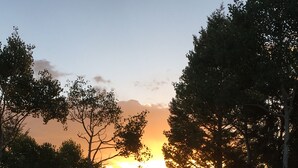 A sunset view through a forest with a wooden deck. - Quiet mountain escape with great views. (Cimarron)