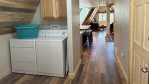 A laundry area with a washing machine and dryer, wooden cabinets, and a dining area with a table and chairs. - Quiet mountain escape with great views. (Cimarron)