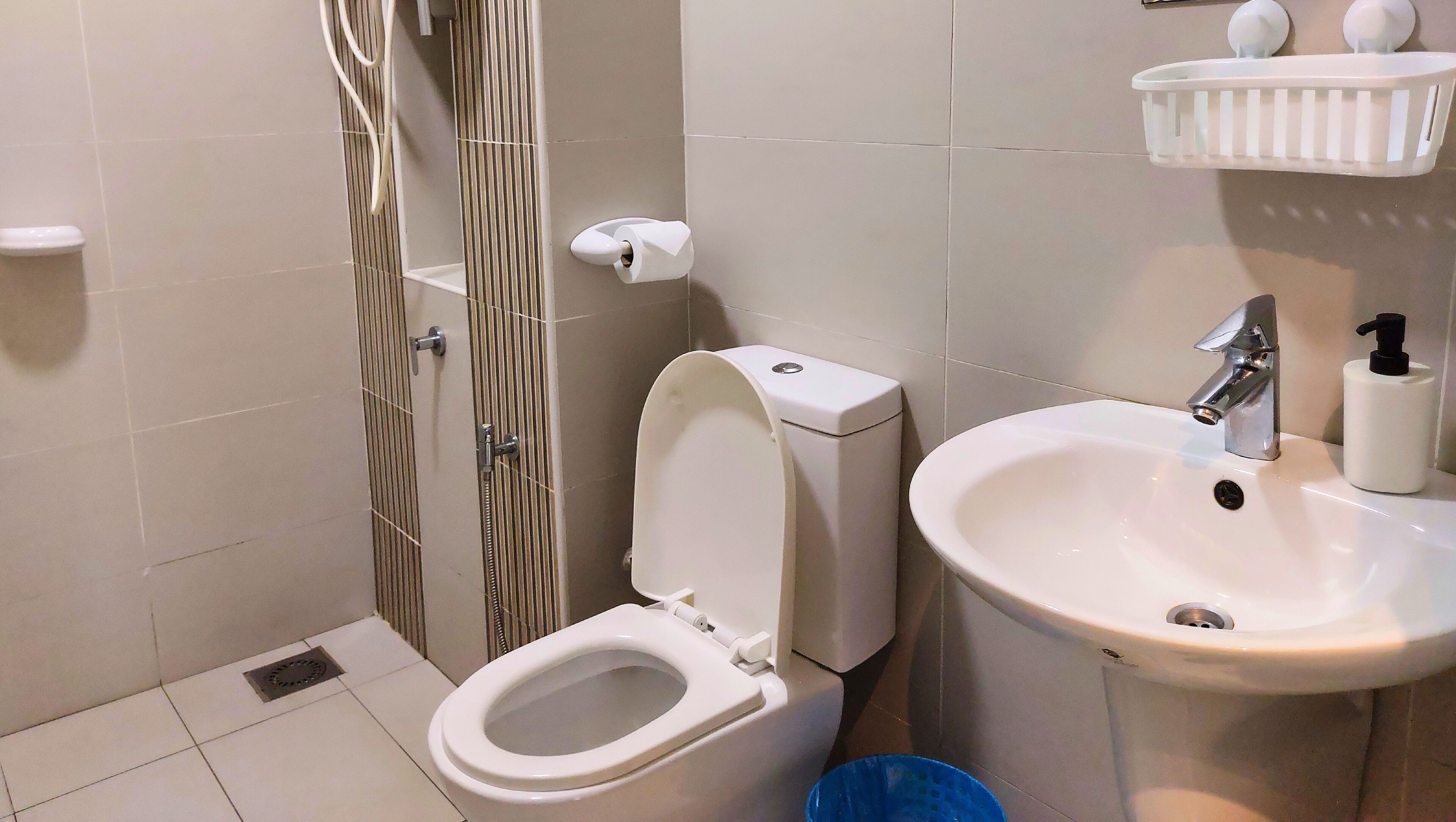 Une salle de bain comprenant des toilettes, un bidet, un lavabo et un espace douche.