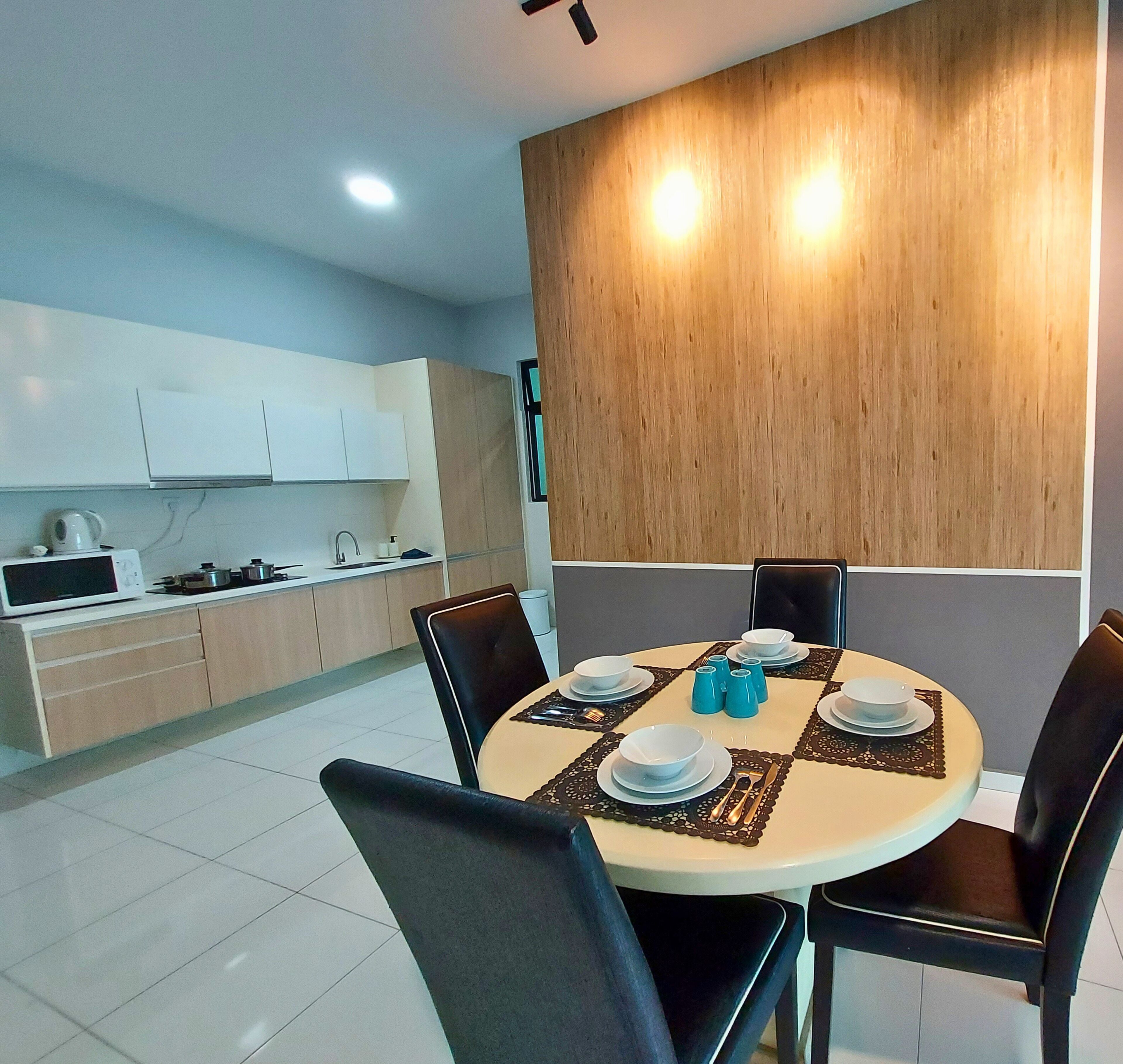 A modern kitchen with white cabinets, a microwave, and a stove. There is a dining area with a round table set for four, featuring blue salt and pepper shakers.