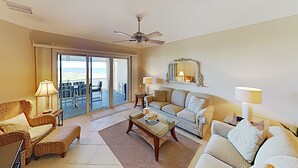 A spacious living room with a balcony, a ceiling fan, and a large mirror.