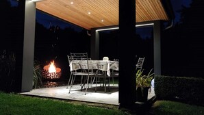 An outdoor patio area with a table and chairs, a fire feature, and a potted plant.