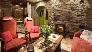 A cozy room with a stone wall, a fireplace, a red chair, and a wooden table.