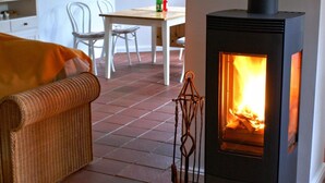 A cozy room with a fireplace, wicker furniture, and a dining area.
