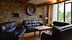 Ein gemütliches Wohnzimmer mit Steinwänden, Ledersofas und einem Holztisch.