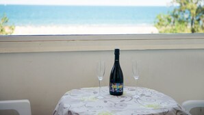 A table with a bottle and two glasses on a tablecloth, overlooking a beach. - Coastal Retreat in Riccione (Riccione)