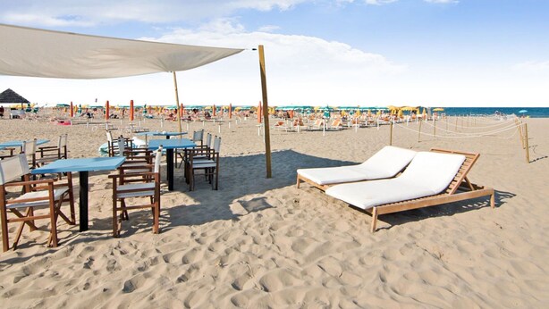 A beachside restaurant with outdoor seating, including tables and chairs, and a shaded area. - Coastal Retreat in Riccione (Riccione)