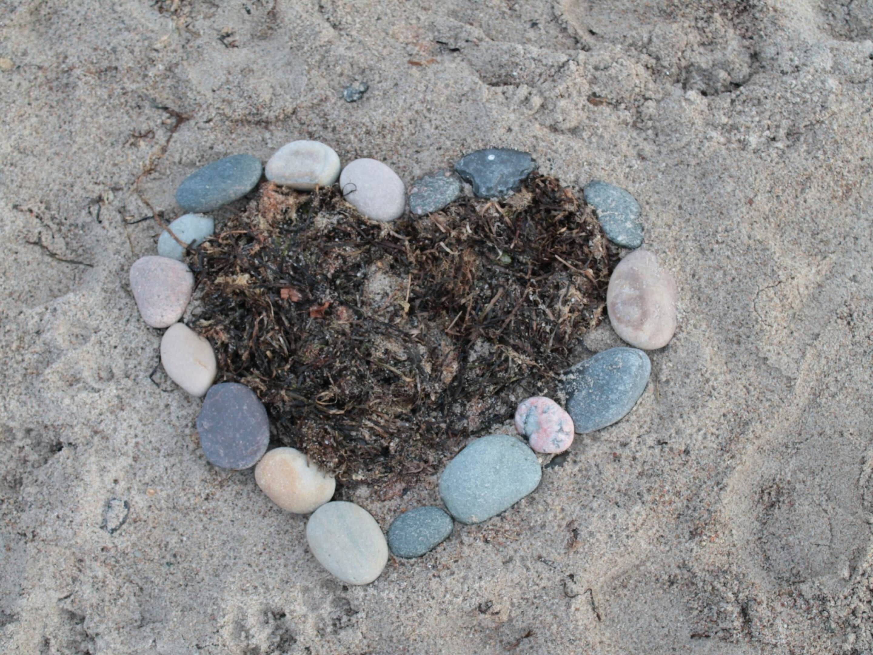Un'accogliente composizione a forma di cuore realizzata con pietre e sabbia sulla spiaggia.