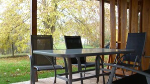 An outdoor wooden deck with a glass table and metal chairs. - Bungalow Borgerende Nahe Strand & Reiten (Boergerende-Rethwisch)