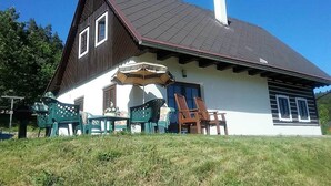 A two-story house with a dark roof and white walls, featuring a patio with outdoor furniture. - Luxury Chalet in Stupna near Ski Area (Vidochov)